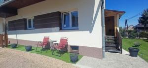 a patio with three chairs and a table in front of a house at Pod Górą in Wiśniowa