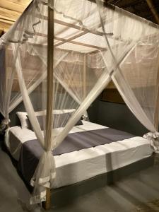 a canopy bed with white mosquito nets on it at Foresta Yala in Tissamaharama
