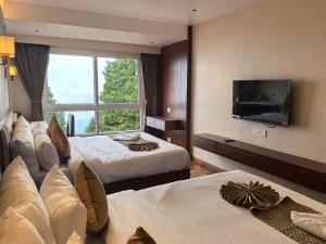 a hotel room with two beds and a flat screen tv at Hotel Old Bellevue Heritage Stay with Mountain Views in Chowrasta Darjeeling in Darjeeling