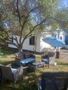 a group of chairs and an umbrella next to a tree at Kuca za odmor Maestral in Privlaka