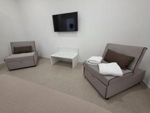 a living room with two chairs and a tv at Piccola Chappy in Taranto +9 photos