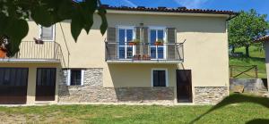 a house with two windows and a balcony with plants at La Paulotta in Paroldo
