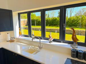 a kitchen counter with a sink and a window at Luxury Norfolk Barn for 12 with Hot Tub , Games Room & EV Car Port in Lenwade +139 photos