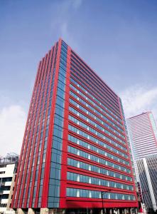a tall red office building in a city at Hotel Villa Fontaine Grand Tokyo-Tamachi in Tokyo
