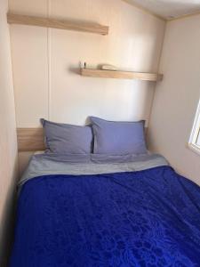 a bed with blue pillows in a small room at Maison de Lucie à Tholen in Poortvliet