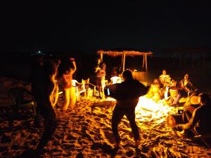 a group of people standing around a fire on the beach at Baafeh in Sanyang
