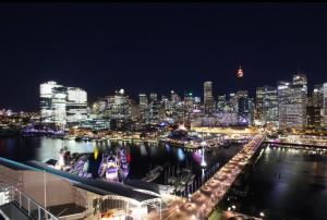 a view of a city at night with a harbor at 3 Bedroom Darling Harbour Apartment in Sydney
