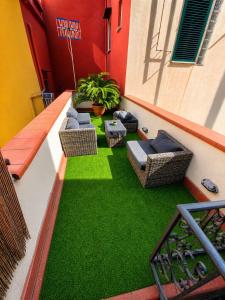 a balcony with green artificial grass and wicker chairs at Mosahouse in Naples