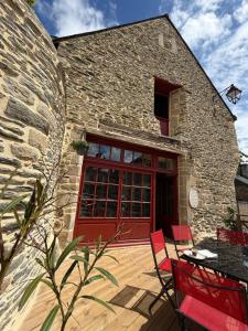 a stone building with a red door and red chairs at Le Gîte du Prieuré in Josselin