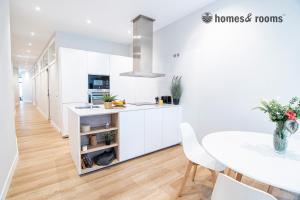 a kitchen with white cabinets and a table and chairs at Enorme apartamento con 4 baños in Santiago de Compostela