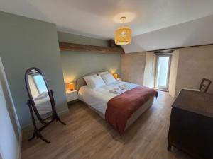 a bedroom with a bed and a dresser and a mirror at Le Gîte du Prieuré in Josselin