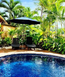 an umbrella and chairs next to a swimming pool at Villas Mimosa at La Ropa Beach in Zihuatanejo
