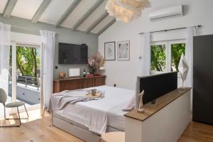 a bedroom with a bed and a tv and windows at Luxury Villa Andrea Vrzika in forest near the sea with heated pool in Zagvozd