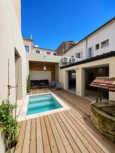 a backyard with a swimming pool on a wooden deck at La Maison des Filles in Agen