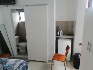 a bedroom with a door leading into a kitchen with a chair at 36 the trout lodge in Goodwood