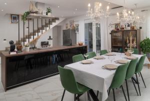 a dining room with a table and green chairs at Luxury Villa Andrea Vrzika in forest near the sea with heated pool in Zagvozd