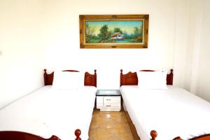 two beds in a room with a picture on the wall at Villa Ekluxe in Delvinë