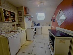 a small kitchen with white appliances and a red wall at L'Orée des Bois in Paliseul