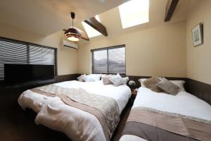 a bedroom with two beds and a flat screen tv at KEI VILLA Tsujido in Takata
