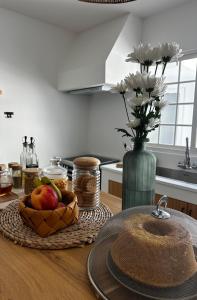 a table with a bowl of fruit and a vase with flowers at Coastal Sands Azores in Ribeira Grande +4 photos