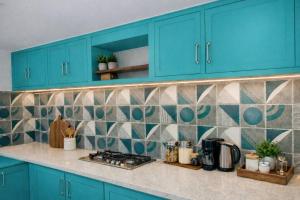 a kitchen with blue cabinets and a tiled wall at BTL Kamakshi homez , 3bhk free parking, open dining, balcony in Ludhiana