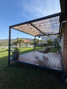 a wooden deck with two chairs and a pergola at Estrela do Gerês - Casa Fernandes in Outeiro