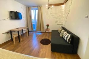 a living room with a black couch and a table at Apartamenty przy Starówce in Olsztyn