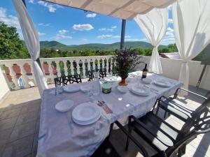 a table with plates and wine glasses on a patio at Apartman Gizdavac in Gizdavac