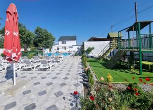 a patio with chairs and a umbrella and a pool at Laguna House next to Pool at Bazaleti Lake in Bazalet'i