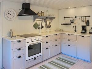 a kitchen with white cabinets and a clock on the wall at 5 person holiday home in Häradsbäck in Ryd +32 photos