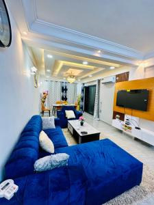 a living room with a blue couch and a flat screen tv at Magnifique Appartement meublé de 2 chambres avec GROUPE ELECTROGENE et ASCENSEUR in Douala