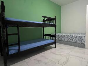 two bunk beds in a room with a green wall at Pousada Açaí in Ilha Comprida