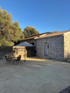 a table and chairs with an umbrella in front of a brick building at Casa Diatsenta in Bogdanátika