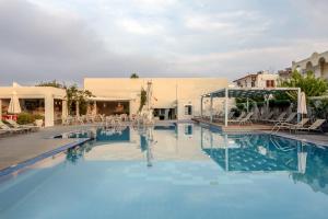 a pool at a hotel with chairs and tables at Nissia Kamares in Kardamaina