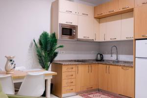 a kitchen with white cabinets and a table and a plant at Hotel Kamomil in Durrës