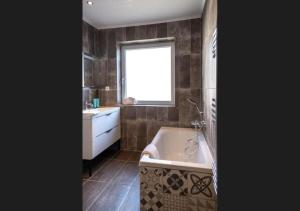 ein Badezimmer mit Badewanne, Waschbecken und Fenster in der Unterkunft Nouveau - L'Entre Nous - Europa Park in Huttenheim