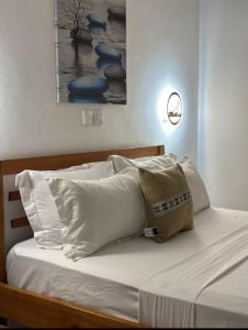 a bed with white sheets and pillows on it at Imani staycations Diani in Diani Beach +18 photos