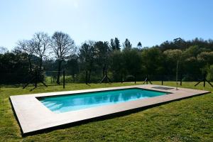a swimming pool in the middle of a grass field at Casas do Campo in Monfero