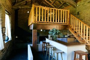 a kitchen with a bar with stools and a staircase at Casas do Campo in Monfero
