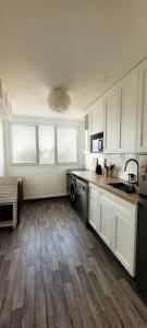 a kitchen with white cabinets and wooden floors at Paris Appartement 2-pièce Master Bedroom Romantique in Alfortville