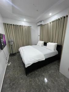 a bedroom with a bed with white sheets and pillows at Kayus Place in Isaga-Abosule