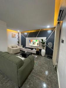 a living room with a couch and a flat screen tv at Kayus Place in Isaga-Abosule