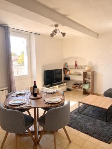 a living room with a table with chairs and a television at Charmant T3 au centre de gréoux les bains in Gréoux-les-Bains