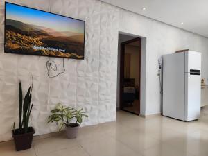 a television hanging on a wall with a refrigerator at Aluguel por Temporada Marabá - São Félix in Marabá