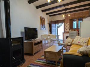 a living room with a couch and a tv and a table at Acogedora casa en Pampaneira in Pampaneira