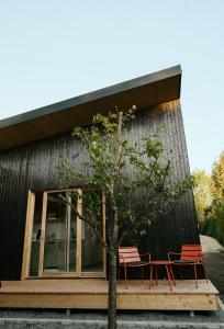 a house with two chairs and a tree in front of it at Mokuzo Tiny Houses in Lauingen