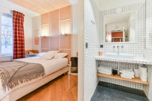a bedroom with a bed and a sink and a mirror at Hotel Habituel in Paris