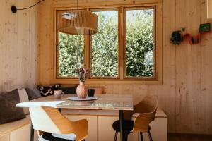 a kitchen with a table and chairs and two windows at Mokuzo Tiny Houses in Lauingen +12 photos