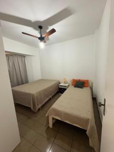 two beds in a room with a ceiling fan at Espaço tranquilo e de lazer em Guarujá in Guarujá