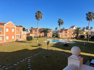 a house with a yard with a pool and palm trees at Apartamento en Olivanova in Casas Devesa